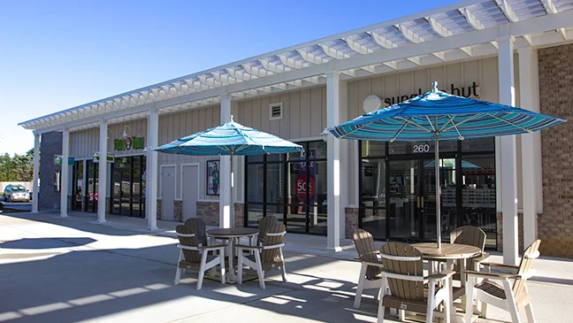 Featured image for “Tanger Outlets Bayside: Low Maintenance Trex Pergolas with Fixed Canopies”Shade structures shield shoppers walking to the newly renovated restrooms and provides a seamless, dry transition between stores. Trex Pergola with ShadeRight Fixed canopy was the ideal choice for form and function and helped complete the update.12663:full
