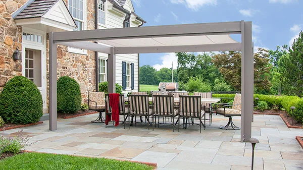 Brown Jordan pergola with tensioned shade canopy on a paver patio